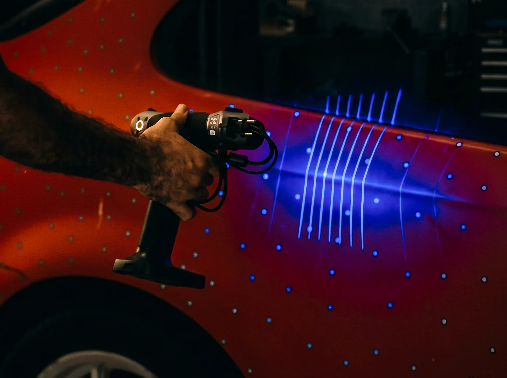 Handheld 3D scanner tracing laser lines across a car's bodywork